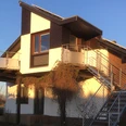 Ferienwohnung Ruhepol Zweistöckige Ferienwohnung mit moderner Fassade, Balkon und Außentreppe unter blauem Himmel.