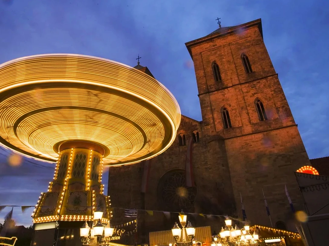 Maiwoche Ein leuchtendes Karussell dreht sich vor einer beleuchteten Kirche während der abendlichen Maiwoche.