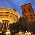 Maiwoche Ein leuchtendes Karussell dreht sich vor einer beleuchteten Kirche während der abendlichen Maiwoche.