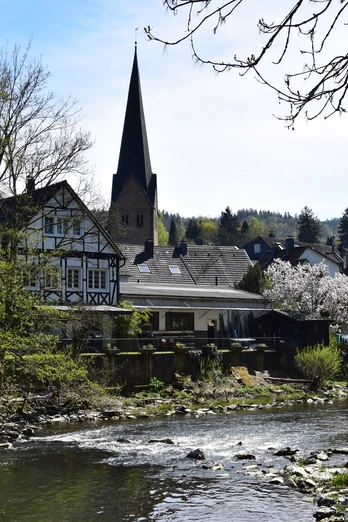 Agger in Ründeroth idyllisches Fachwerkdorf Engelskirchen an der Agger mit Kirche und blühenden Bäumen im Frühling.