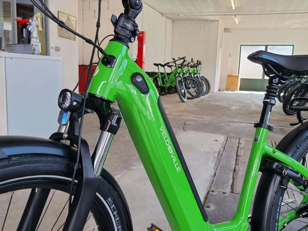 e-bike-verleih-bad-zwischenahn-nahaufnahme.jpg Ein leuchtend grünes E-Bike steht in einem hellen Raum mit weiteren Fahrrädern im Hintergrund.