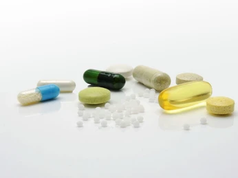 Medizin und Ganzheitliche Ansätze in Kombination Verschiedene Tabletten und Kapseln in unterschiedlichen Farben und Formen auf weißem Hintergrund.