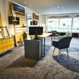 Schröder Optik & Kurzhals GmbH Helles Optikergeschäft mit Brillenregalen aus Holz, grauen Sesseln und großen Schaufenstern.