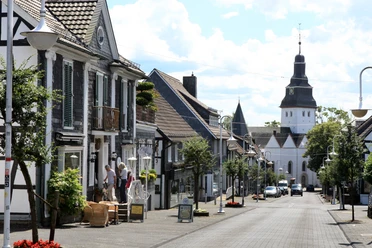 Ortskern Nümbrecht <p>Historische Fachwerkhäuser in Nümbrecht, ruhige Straße mit Fußgängern. Kirche im Hintergrund.</p>