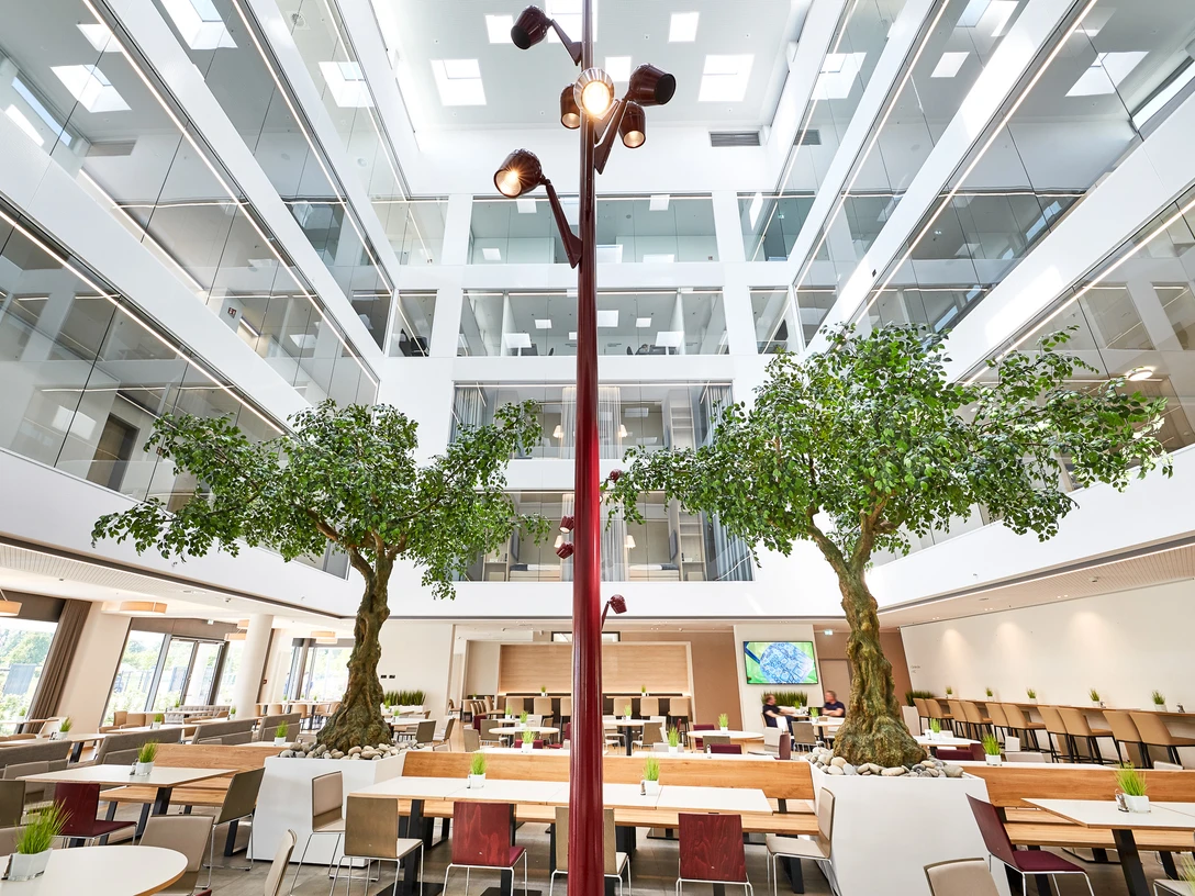 Hotel Vivendi Großzügiger, lichtdurchfluteter Lobbybereich mit Bäumen und modernen Sitzgelegenheiten im Zentrum.