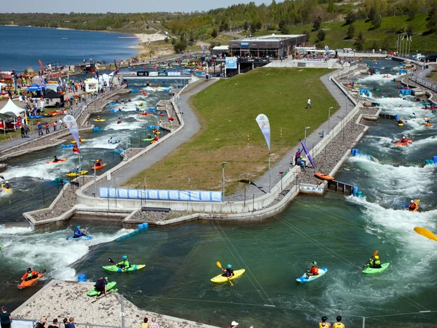 View of the white water facility in the Markkleeberg Canoe Park for the paddling festival with numerous sports enthusiasts in canoes on the water, water sports, leisure activity