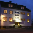 Das Hotel Kaup bei Nacht, beleuchtet und umgeben von Bäumen, mit gut erkennbarer Eingangstür.