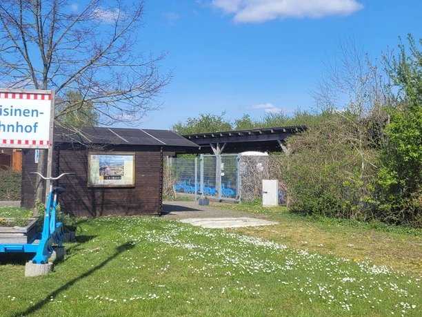 Draisinen Blauer Draisinenschienenwagen auf Rasen vor einem kleinen Holzgebäude mit Draisinen-Bahnhof-Schild.