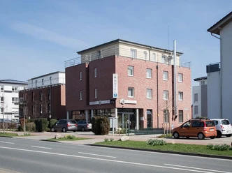 Dreistöckiges Backsteinhotel mit moderner Architektur, Parkplatz und Eingang auf urbaner Straßenecke.