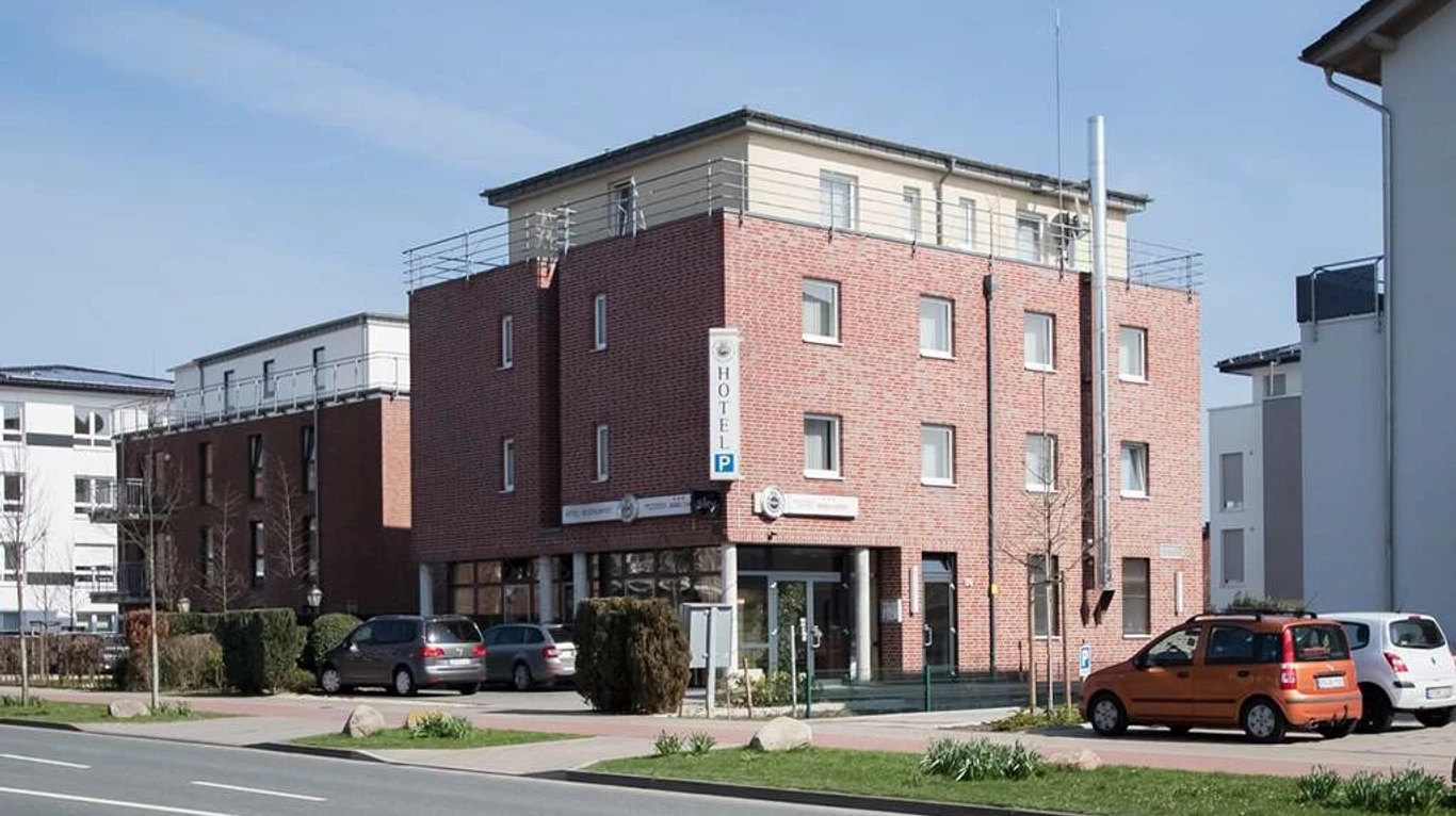 Hotel Manu Dreistöckiges Backsteinhotel mit moderner Architektur, Parkplatz und Eingang auf urbaner Straßenecke.
