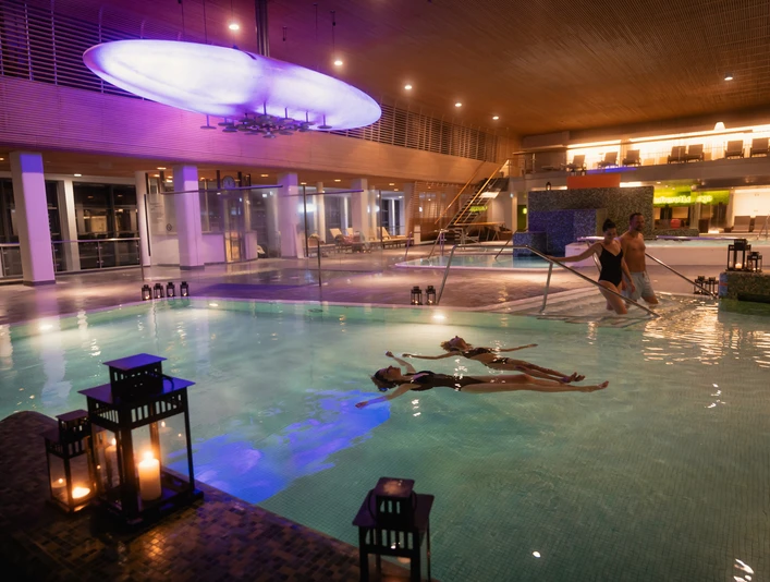 VitaSol Therme in Bad Salzuflen Ein beleuchtetes Innenpool der VitaSol Therme mit Gästen beim Schwimmen, umgeben von Kerzenlicht.