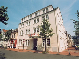 Arthotel ANA Fleur Vierstöckiges Arthotel ANA Fleur im klassischen Stil, umgeben von Bäumen, unter blauem Himmel.