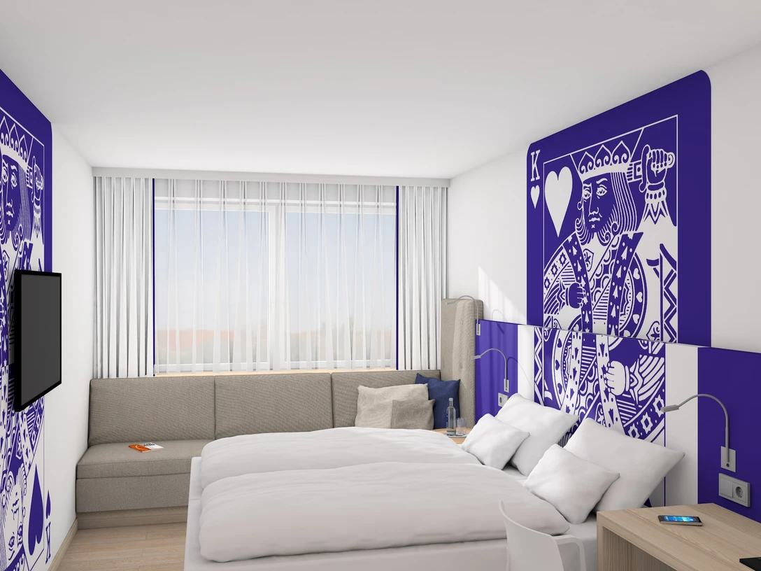 IBB Blue Hotel Paderborn Moderne Hotelzimmer mit Doppelbett, stilvolle Kunst an Wänden, Sofa, Schreibtisch und großem Fenster.