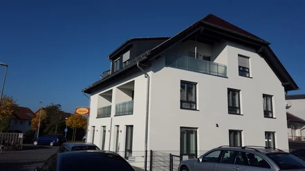 Zimmervermietung Aras Ein modernes zweistöckiges Gebäude mit weißer Fassade und Balkonen, umgeben von Autos.