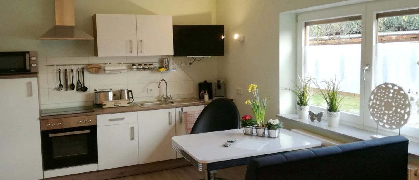 Gästezimmer am Lippesee Moderne Küche in einer Ferienwohnung mit Esstisch, weißen Schränken und Blick auf ein Fenster.