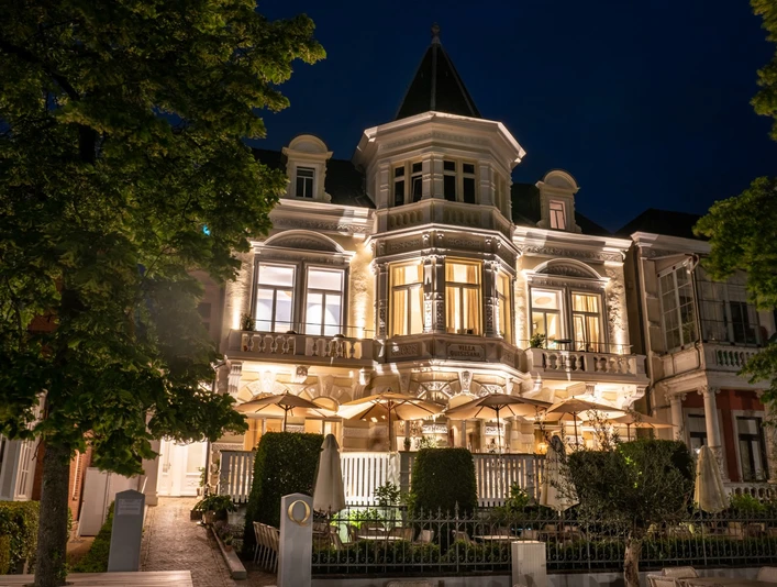 Villa Q Außenansicht Die Villa Q leuchtet in der Nacht. Ihre Architektur wird durch gezielte Beleuchtung hervorgehoben, was sie zu einem auffälligen Anblick macht.