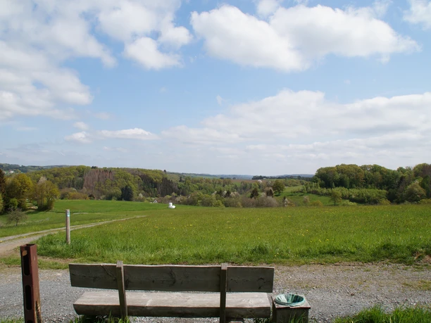 Bank mit Blick auf Geilenkausen Eine Holzbank mit Blick auf weite grüne Felder und einen bewölkten Himmel in Waldbröl.