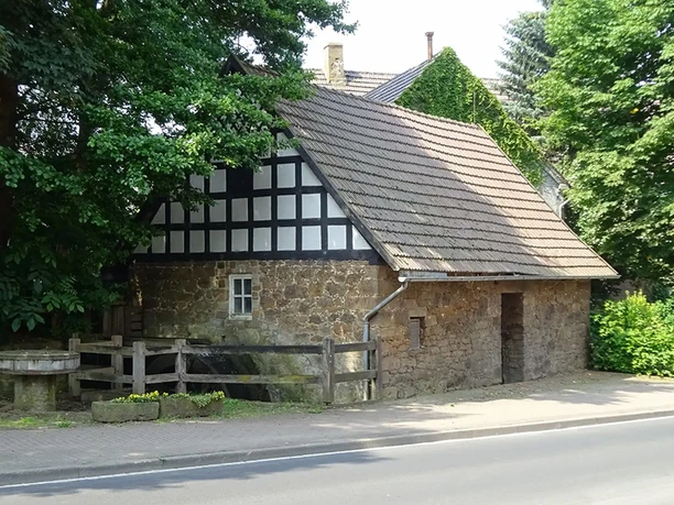 Weiße Fachwerkbalken zieren die historische Wassermühle Eilhausen mit ihrem steinernen Mauerwerk.