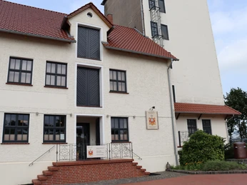 BrennerEy Eingang eines zweistöckigen Gebäudes mit rotem Dach, mehreren Fenstern, Rampe und Treppenstufen.