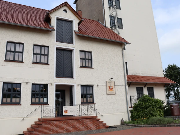 BrennerEy Eingang eines zweistöckigen Gebäudes mit rotem Dach, mehreren Fenstern, Rampe und Treppenstufen.