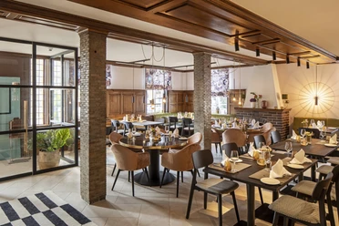 Restaurant Hotel WunnersWat.jpg Gemütliches Restaurant mit eleganter Holzausstattung, gedeckten Tischen und gemütlicher Atmosphäre.