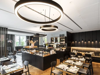 Frühstücksraum Hotel WunnersWat.jpg Modern gestaltetes Restaurant mit eleganter, minimalistischer Einrichtung, stilvollen Leuchten und gedeckten Tischen.