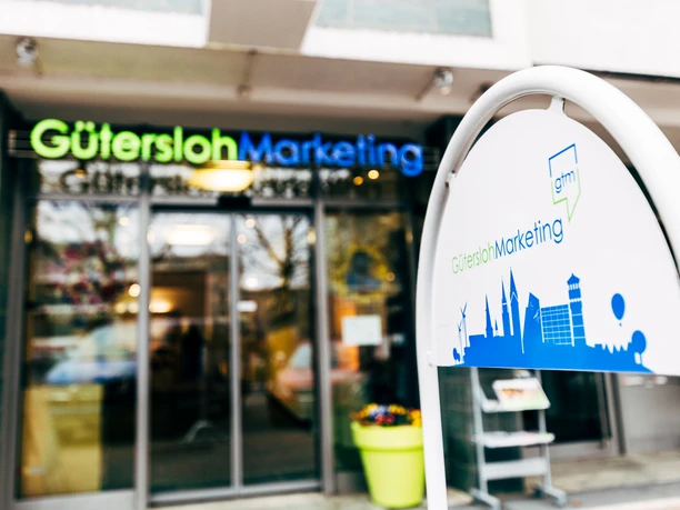 Eingangsbereich von Gütersloh Marketing mit modernem Logo und stilisierter Stadt-Silhouette auf Schild.