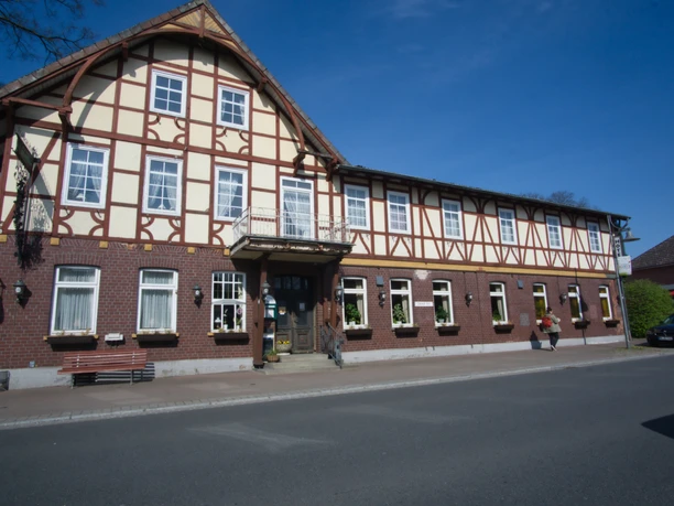 Außenansicht Fehlhaber Traditionsreicher Fachwerkbau mit roter Backsteinfassade und weißen Sprossenfenstern an der Straße.