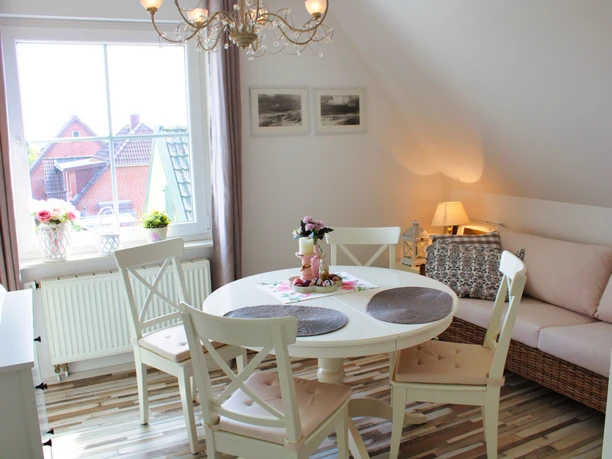 Esszimmer Helles Esszimmer mit rundem Tisch, weißen Stühlen und kleinem Sofa am Fenster.