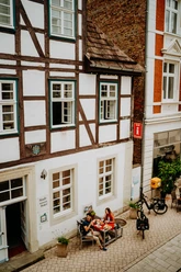 Teutoburger Wald-Brakel-Tourist Info ┬® Teutoburger Wald Tourismus (3).jpg Fachwerkhaus in Brakel mit Touristen-Information; Menschen sitzen vor dem Gebäude in der Fußgängerzone.