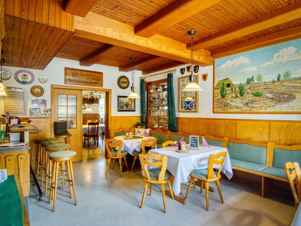 Restaurant Innenraum des Restaurants Landgasthaus Eichenkrug mit Holzbalkendecke und Wandgemälde der Heide.