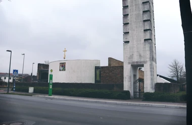 IMG_0494.JPG Kirche mit modernem Turm, umgeben von Straßen und Bäumen unter grauem Himmel. Ruhige Umgebung im Bild.