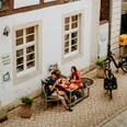 Zwei Personen genießen ein Essen im Freien vor einem historischen Fachwerkgebäude in Brakel.