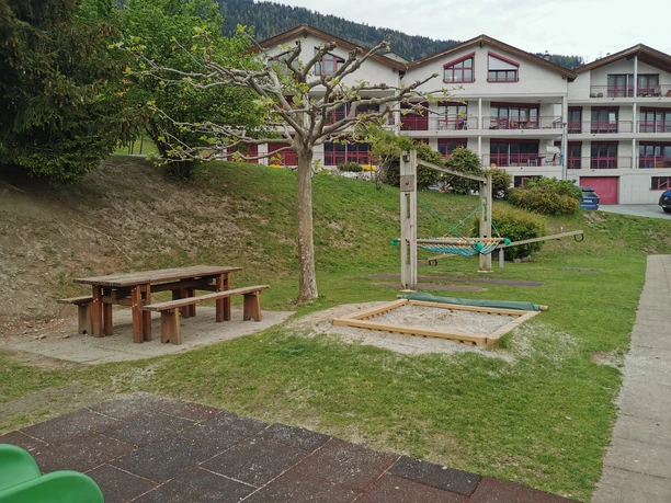 Spielplatz-Ried-Brig-Schulhaus (1).jpg Image d'un bac à sable, d'une balançoire et d'une table