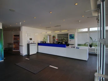 Ein heller, moderner Empfangsbereich mit blauer Theke, Wartebereich und freundlicher Atmosphäre.