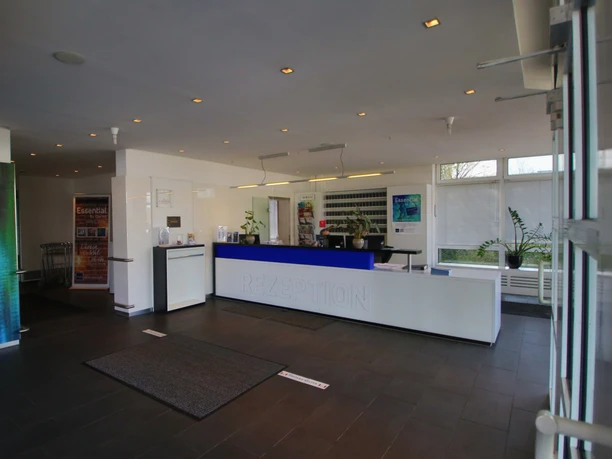 Rezeption Ein heller, moderner Empfangsbereich mit blauer Theke, Wartebereich und freundlicher Atmosphäre.