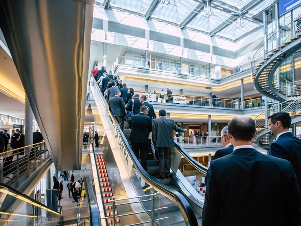 Escalator in the foyer of the event venue Congress Center Leipzig | Leipzig Convention Bureau People riding the escalator in the foyer of the event venue Congress Center Leipzig – presented by Leipzig Convention Bureau
