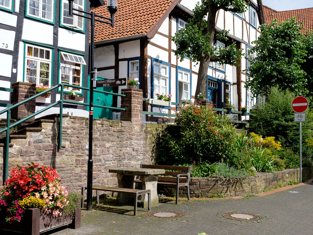 Brink Fachwerkhäuser mit roten Ziegeldächern und bunter Blumenschmuck prägen eine ruhige Straßenszene.