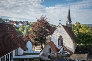 St Stephan Die Kirche St. Stephan mit ihrem markanten Kirchturm ist umgeben von Bäumen und alten Gebäuden.