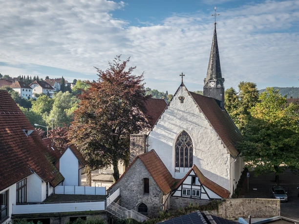 St Stephan Die Kirche St. Stephan mit ihrem markanten Kirchturm ist umgeben von Bäumen und alten Gebäuden.