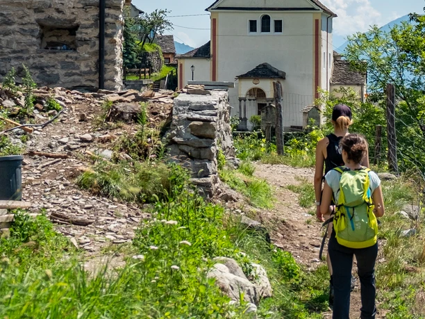 Wanderer in Richtung Dorf mit Kirche Wanderer in Richtung Dorf mit Kirche