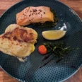 Lachsgericht Lachsfilet auf einem Bett aus grünem Gemüse mit Kartoffelgratin, Kirschtomate und Zitronenspalte.Salmon fillet on a bed of green vegetables with potato gratin, cherry tomato and lemon wedge.Laksefilet på en bund af grønne grøntsager med kartoffelgratin, cherrytomat og citronbåd.Zalmfilet op een bedje van groene groenten met aardappelgratin, cherrytomaat en citroenpartjes.
