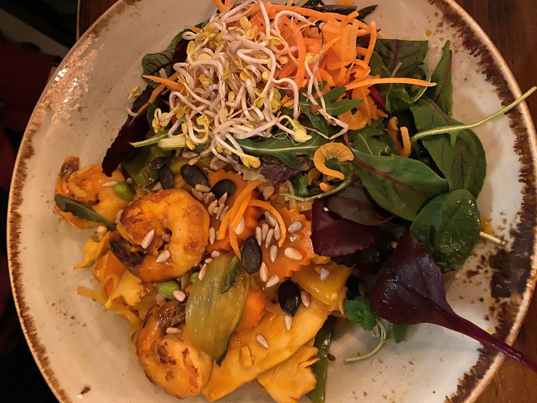 Exotische Hähnchenpfanne mit Garnelen, knackigem Gemüse, Kernen und frischen Sprossen serviert.