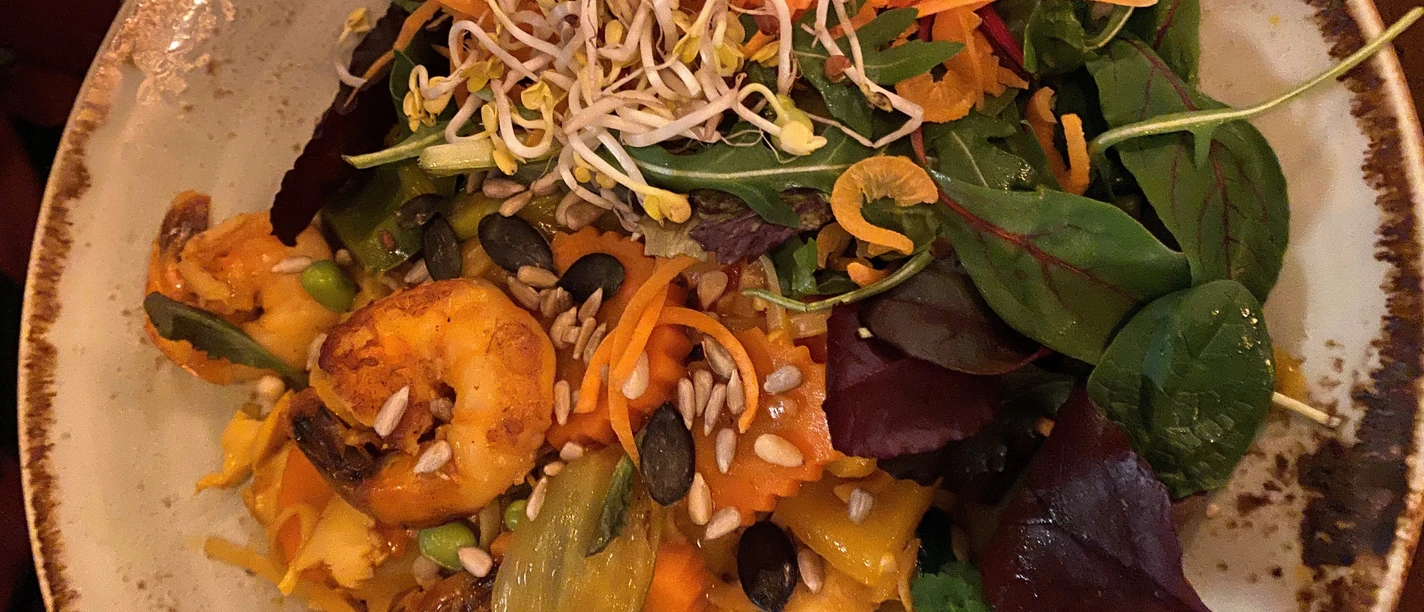 Hähnchengericht Exotische Hähnchenpfanne mit Garnelen, knackigem Gemüse, Kernen und frischen Sprossen serviert.