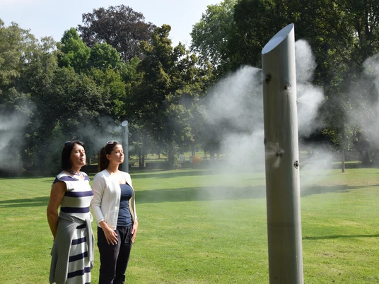 2016-09-01_Nebelsäule.JPG Menschen stehen in einem Park vor einer Nebelskulptur aus Metall, die Wassernebel sprüht.