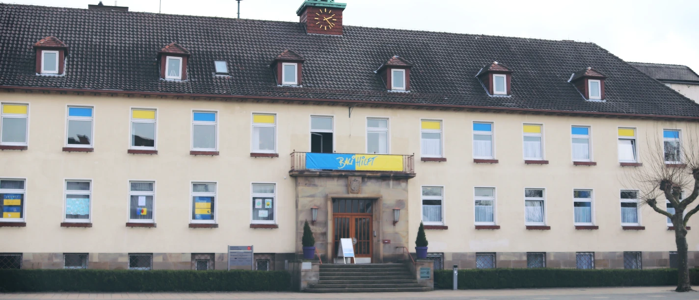 IMG_0065.JPG Kommunalgebäude mit gelb-blauen Flaggen über dem Eingang, großer leerer Platz im Vordergrund.