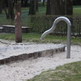 IMG_0429.JPG Wasserspielbereich mit schlangenförmigem Wasserhahn in einem Park, umgeben von Sand und Rasen.