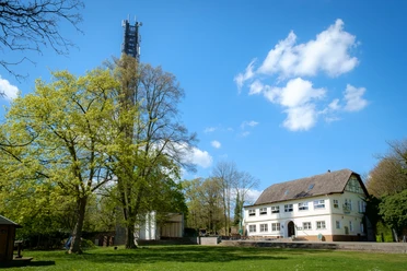 El Castillo Ein weißes Gebäude mit Satteldach steht neben einem hohen Turm, umgeben von grünen Bäumen.