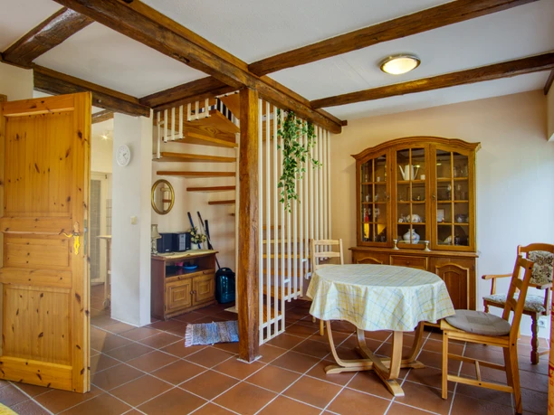 essbereich-seiler.jpg Heller Essbereich mit Holztisch, Vitrinenschrank, Holztreppe und sichtbaren Deckenbalken.