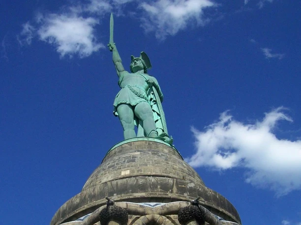Hermannsdenkmal_Teutoburger Wald Tourismus_Bohlken_1600.jpg Blick auf das Hermannsdenkmal im Teutoburger Wald, mit erhobenem Schwert vor blauem Himmel.